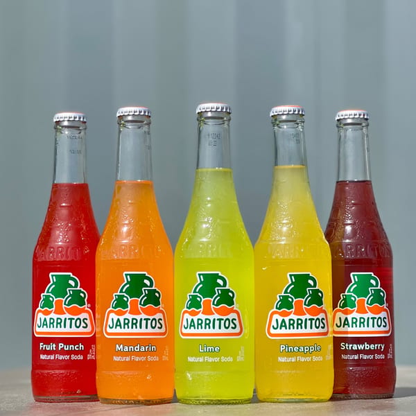 Five colorful Jarritos sodas, including Fruit Punch, Mandarin, Lime, Pineapple, and Strawberry flavors.